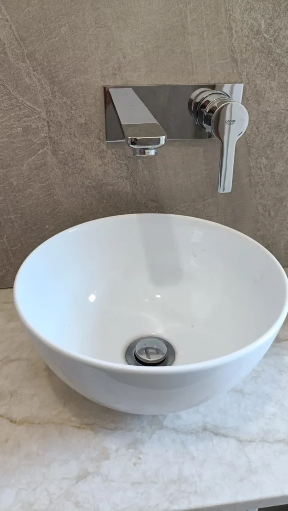 Bateria podtynkowa przy umywalce i miska WC w łazience wykończonego domu w Sławkowicach pod Krakowem.