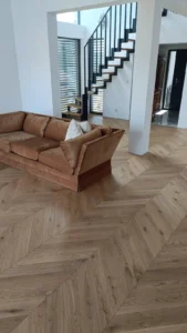 Salon z drewnianą podłogą, schodami i strefą wypoczynkową w wykończonym domu pod klucz w Sławkowicach pod Krakowem.