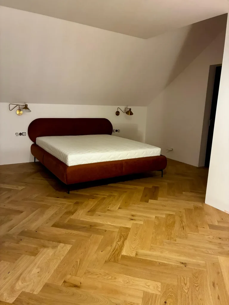 Sypialnia z drewnianą podłogą i łóżkiem w wykończonym domu pod klucz w Sławkowicach pod Krakowem.